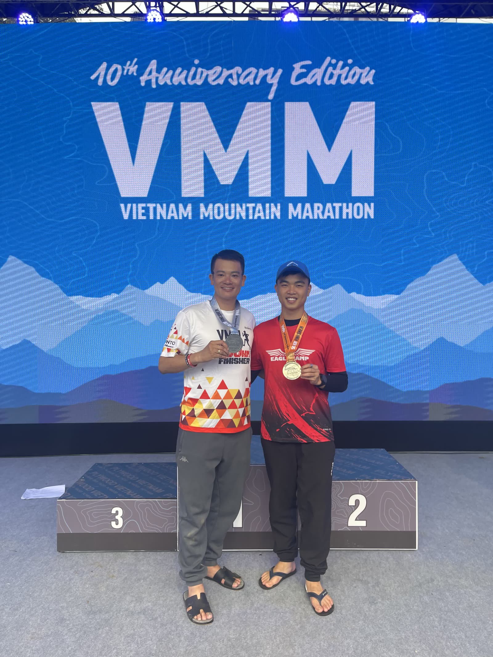 Bìa bài: Hùng và anh Ngọc Anh trên bục VMM (Vietnam Mountain Marathon) 10th Anniversary Edition, cùng cầm huy chương finisher