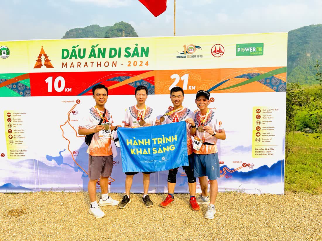 Bốn người đeo huy chương cầm lá cờ Hành Trình Khai Sáng trước phông giải Dấu Ấn Di Sản Marathon 2024